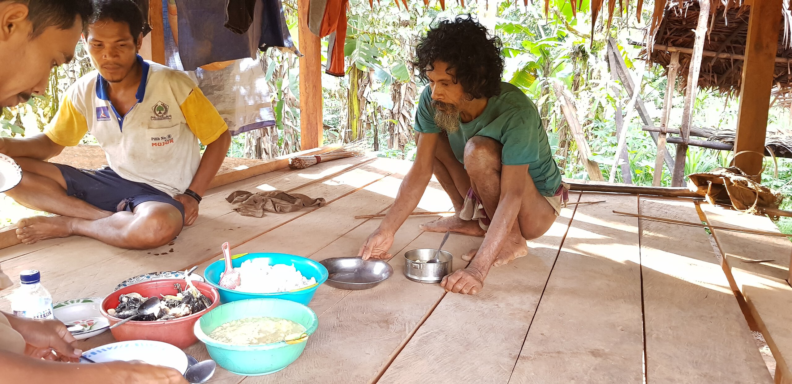 Pak Pojiji, the oldest Togutil in the settlement (right) is having a lunch with his guests. His house was built for him by Antam, a company mining nickel in Halmahera.